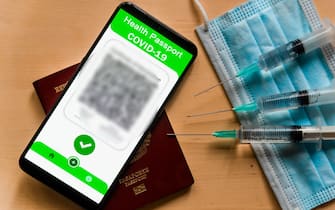 In this illustrative photo a symbolic Covid certificate, also called covid vaccine pass, is seen on the screen of a mobile phone with three syringes and a face mask in Barcelona, Spain on November 24, 2021. More and more countries are adopting the Covid19 vaccination passport to restrict access to public spaces to vaccinated people, in many cases after the third vaccine dose, in an effort to contain the spread of covid-19. (Photo by Davide Bonaldo/Sipa USA)