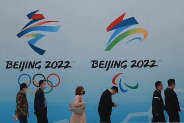 BEIJING, CHINA - APRIL 09:  People wear protective masks as they walk in front the logos of the 2022 Beijing Winter Olympics at National Aquatics Centre on April 9, 2021 in Beijing, China. A "Meet in Beijing" ice test event for the 2022 Winter Olympics will be held from April 1-10.  (Photo by Lintao Zhang/Getty Images)