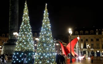 Pedestrians walk by and take pictures of the illuminated Christmas trees on the 'Place Vendome', in Paris, on December 6, 2021 (Photo by Ludovic MARIN / AFP) (Photo by LUDOVIC MARIN/AFP via Getty Images)