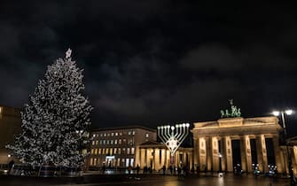 A Christmas tree (L), a giant menorah (C) stand in front of the Brandenburg Gate to celebrate Christmas and Hanukkah on November 29, 2021 in Berlin. (Photo by John MACDOUGALL / AFP) (Photo by JOHN MACDOUGALL/AFP via Getty Images)