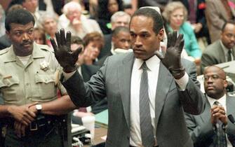 LOS ANGELES, CA - JUNE 21:  O.J. Simpson shows the jury a new pair of Aris extra-large gloves, similar to the gloves found at the Bundy and Rockingham crime scene 21 June 1995, during his double murder trial in Los Angeles,CA. Deputy Sheriff Roland Jex(L) and Prosecutor Christopher Darden (R) look on.  (Photo credit should read VINCE BUCCI/AFP via Getty Images)