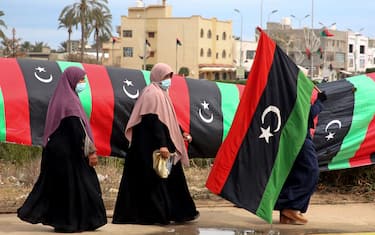 A Libyan woman carries a national flag in the capital Tripoli on February 25, 2021, during celebrations commemorating the 10th anniversary of the 2011 revolution that toppled longtime dictator Moamer Kadhafi. - Libya's prime minister-designate Abdul Hamid Dheibah is set to name a transitional government tasked with unifying the war-torn nation and leading it to elections in December. (Photo by Mahmud TURKIA / AFP) (Photo by MAHMUD TURKIA/AFP via Getty Images)