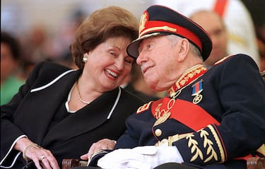 Santiago, CHILE:  (FILE) Picture taken 10 March 1998 of Chile's former dictator (1973-90) general Augusto Pinochet (R) listening to his wife Lucia Hiriart during the ceremony marking his retirement from the army command at the Military Academy in Santiago. Pinochet, 91, died 10 December, 2006 at the Military Hospital in Santiago, where he was admitted a week ago following a heart attack. Accused of fraud and human rights abuses during his regime, Pinochet was first ordered under house arrest in late October on other charges only to be released on parole a few days later in deference to his advanced age and ill health.  AFP PHOTO/CRIS BOURONCLE  (Photo credit should read CRIS BOURONCLE/AFP via Getty Images)