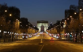 TOPSHOT - A picture shows the empty Champs-Elysees Avenue and the Arc de Triomphe in Paris, at night on March 24, 2020, on the eight day of a lockdown aimed at curbing the spread of the COVID-19 (novel coronavirus) in France. (Photo by Ludovic MARIN / AFP)