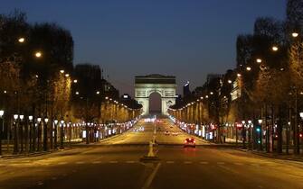 TOPSHOT-FRANCE-HEALTH-VIRUS TOPSHOT - A picture shows the empty Champs-Elysees Avenue and the Arc de Triomphe in Paris, at night on March 24, 2020, on the eight day of a lockdown aimed at curbing the spread of the COVID-19 (novel coronavirus) in France. (Photo by Ludovic MARIN / AFP)