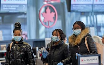 epa08298489 Passengers in masks at the Air Canada counter at an almost empty Montreal-Pierre Elliott Trudeau International Airport in Montreal, Canada, 16 March 2020. The Quebec government announce  the new rule about a second border test to slow the spread of the pandemic of coronavirus.  To date there are 373 confirmed cases of COVID-19 coronavirus in Canada.  EPA/ANDRE PICHETTE