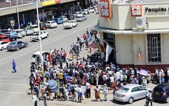 epa09625819 Hordes of people wait outside a bank to withdraw their salaries in Harare, Zimbabwe, 06 December 2021. This has been the situation for over a week as people are waiting for hours and days to get cash.  EPA/AARON UFUMELI