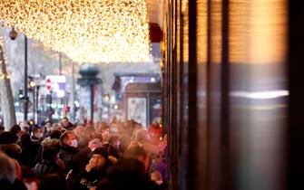 epa09647270 Pedestrians wearing protective face masks walk past shopping mall in Paris, France, 17 December 2021. France is seeing new infection cases spike at nearly 60,000 every 24 hours.  EPA/YOAN VALAT