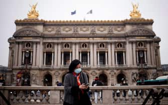 epa09647269 A pedestrian wearing a protective face mask walk past the Opera Garnier in Paris, France, 17 December 2021. France is seeing new infection cases spike at nearly 60,000 every 24 hours.  EPA/YOAN VALAT