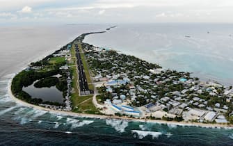 1193312405 FUNAFUTI, TUVALU - NOVEMBER 28: An aerial view of downtown and the airport runway, between the Pacific Ocean (L) and lagoon (R), on November 28, 2019 in Funafuti, Tuvalu. The low-lying South Pacific island nation of about 11,000 people has been classified as â extremely vulnerableâ to climate change by the United Nations Development Programme. The worldâ s fourth-smallest country is struggling to cope with climate change related impacts including five millimeter per year sea level rise (above the global average), tidal and wave driven flooding, storm surges, rising temperatures, saltwater intrusion and coastal erosion on its nine coral atolls and islands, the highest of which rises about 15 feet above sea level. In addition, the severity of cyclones and droughts in the Pacific Island region are forecast to increase due to global warming. Some scientists have predicted that Tuvalu could become inundated and uninhabitable in 50 to 100 years or less if sea level rise continues. The country is working toward a goal of 100 percent renewable power generation by 2025 in an effort to curb pollution and set an example for larger nations. Tuvalu is also exploring a plan to build an artificial island. (Photo by Mario Tama/Getty Images)