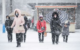 Pedestrians walk on a street as it snows in Pyongyang on December 18, 2021. (Photo by KIM Won Jin / AFP) (Photo by KIM WON JIN/AFP via Getty Images)