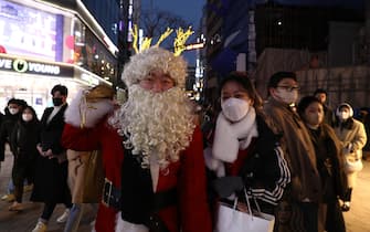 SEOUL, SOUTH KOREA - DECEMBER 25: A South Korean man wears a Santa Claus costume at the Myeongdong shopping district during Christmas on December 25, 2021 in Seoul, South Korea. Government expressed concerns about some religious establishments preparing for year-end events and gatherings ahead of Christmas and asked such facilities to strictly follow the state-mandated disease control measures. Under the new Covid measures, which will be in effect from Saturday until Jan. 2, the use of restaurants and cafes will be restricted to up to four vaccinated people per visit. Bars, nightclubs and other entertainment venues will also be subject to the 9 p.m. (Photo by Chung Sung-Jun/Getty Images)