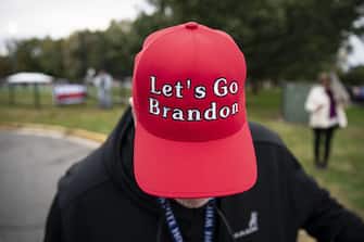 A supporter of former U.S. President Donald Trump displays a "Let's Go Brandon" hat before a campaign event for Terry McAuliffe, Democratic gubernatorial candidate for Virginia, in Arlington, Virginia, U.S., on Tuesday, Oct. 26, 2021. McAuliffe, a former Virginia governor is locked in a dead heat with Glenn Youngkin, a former co-chief executive officer of Carlyle Group Inc., ahead of next week's election. Photographer: Al Drago/Bloomberg via Getty Images