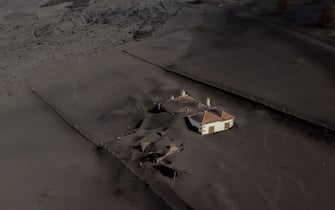 TOPSHOT - This aerial picture shows a house covered with lava and ashes following the eruption of the Cumbre Vieja volcano, in Las Manchas, on the Canary Island of La Palma on December 14, 2021. - The Cumbre Vieja volcano has been erupting since September 19, forcing more than 6,000 people out of their homes as the lava burnt its way across huge swathes of land on the western side of La Palma. (Photo by JORGE GUERRERO / AFP) (Photo by JORGE GUERRERO/AFP via Getty Images)