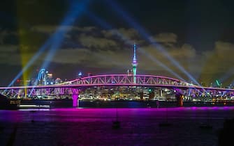 AUCKLAND, NEW ZEALAND - JANUARY 01: A light show from the Skytower and harbour bridge during Auckland New Year's Eve celebrations on January 01, 2022 in Auckland, New Zealand. The light show named 'Auckland Is Calling' replaces the normal fireworks due to government COVID-19 restrictions but signifies a welcome to visitors from New Zealand and eventually the world to the region . (Photo by Dave Rowland/Getty Images for Auckland Unlimited)