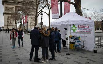 epa09660394 People queue at a pop-up COVID-19 antigenic testing site on the Champs-Elysees in central Paris, France, 30 December 2021. The number of new COVID-19 cases is surging past 200,000 per day, prompting the city of Paris to reinstate mandatory mask-wearing outdoors as of 31 December.  EPA/IAN LANGSDON