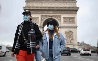 epa09660395 Pedestrians wearing face masks walk on the Champs-Elysees in central Paris, France, 30 December 2021. The number of new COVID-19 cases is surging past 200,000 per day, prompting the city of Paris to reinstate mandatory mask-wearing outdoors as of 31 December.  EPA/IAN LANGSDON