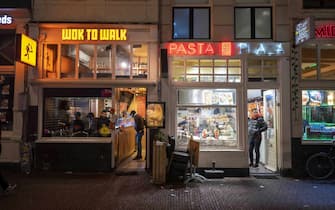 epa09609746 Customers at takeout restaurants in Amsterdam, The Netherlands, 28 November 2021. Dutch authorities tightened restrictions amid a surge of new Covid-19 cases and concerns over the new B.1.1.529 coronavirus variant Omicron. Among the new measures is a closing time for cultural venues and events, such as cinemas and cafes, between 5:00 PM and 5:00 AM local time.  EPA/EVERT ELZINGA