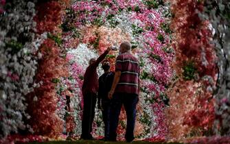epa09559476 People take photos in a flower tunnel on the occasion of the Day of the Dead, at the Jardim da Saudade cemetery in Rio de Janeiro, Brazil, 02 November 2021. The Jardim da Saudade cemetery, located in the northern part of the city, recently built a tunnel with 70,000 flowers to honor the more than 68,000 victims of covid-19 in the state of Rio de Janeiro.  EPA/Antonio Lacerda