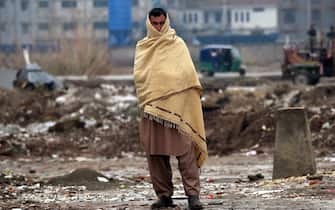 Una persona si ripara dal gelo in Pakistan