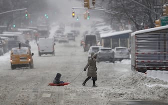 epaselect epa09716908 A woman pulls a child in a snow sled acroos Ninth Avenue in New York, New York, USA, 29 January 2022. The large storm is hitting a substantial portion of the East Coast of the United States, disrupting travel and some areas are forecast to receive up to 2 feet (61 centimeters) of snow.  EPA/Peter Foley