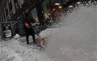 epa09716907 A worker clears snow from a sidewalk with a snowblower on West 57th street in New York, New York, USA, 29 January 2022. The large storm is hitting a substantial portion of the East Coast of the United States, disrupting travel and some areas are forecast to receive up to 2 feet (61 centimeters) of snow.  EPA/Peter Foley