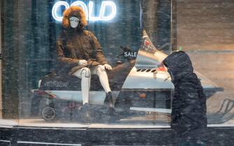 epa09716641 A pedestrian walks past a store display for winter gear, in Boston, Massachusetts, USA, 29 January 2022. A winter storm is expected to bring up to 40in (102cm) of snow to the east coast areas of Massachusetts, along with extreme high tides and flooding.  EPA/CJ GUNTHER