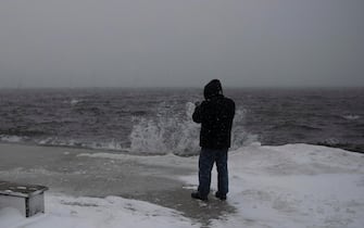epa09716651 A pedestrian pauses to make photographs of the waves crashing at Fan Pier, in Boston, Massachusetts, USA, 29 January 2022. A winter storm is expected to bring up to 40in (102cm) of snow to the east coast areas of Massachusetts, along with extreme high tides and flooding.  EPA/CJ GUNTHER