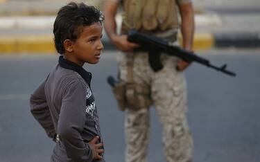 A Yemeni boy stands next to a Saudi soldier in the southern city of Aden on September 26, 2015. Riyadh has been launching air strikes against the Shiite Huthi rebels in Yemen to support the internationally-backed government of Yemeni President Abedrabbo Mansour Hadi, which was losing ground, with  Saudi Arabia fearing the Huthis would take over all of Yemen and move its neighbour into the orbit of the Sunni kingdom's Shiite regional rival Iran. AFP PHOTO / AHMED FARWAN        (Photo credit should read AHMED FARWAN/AFP via Getty Images)