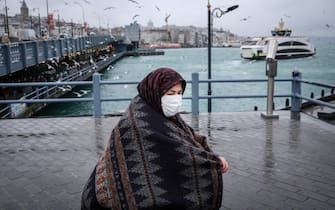epa09680252 A woman wearing a protective facemask walks next to Galata Bridge on a rainy day,  in Istanbul, Turkey, 12 January 2022. Turkey has recorded 74,266 new COVID-19 cases in last 24 hours, its highest daily figure of the pandemic.  EPA/SEDAT SUNA