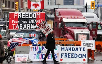 A protester walks in front of parked trucks as demonstrators continue to protest the vaccine mandates implemented by Prime Minister Justin Trudeau on February 8, 2022 in Ottawa, Canada. (Photo by Dave Chan / AFP) (Photo by DAVE CHAN/AFP via Getty Images)