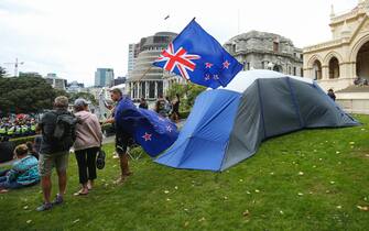 WELLINGTON, NEW ZEALAND - FEBRUARY 10: Protesters stand next to a tent during a protest at Parliament on February 10, 2022 in Wellington, New Zealand. Anti-vaccine and Covid-19 mandate protesters were broken up by police after three days of demonstrations outside Parliament. (Photo by Hagen Hopkins/Getty Images)
