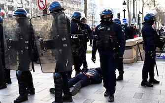 French anti-riot policemen detain a man on the Champs Elysees in Paris on February 12, 2022 as convoys of protesters so called "Convoi de la Liberte" arrived in the French capital. - Thousands of protesters in convoys, inspired by Canadian truckers paralysing border traffic with the US, were heading to Paris from across France on February 11, with some hoping to blockade the capital in opposition to Covid-19 restrictions despite police warnings to back off. The protesters include many anti-Covid vaccination activists, but also people protesting against fast-rising energy prices that they say are making it impossible for low-income families to make ends meet. (Photo by Sameer Al-DOUMY / AFP) (Photo by SAMEER AL-DOUMY/AFP via Getty Images)