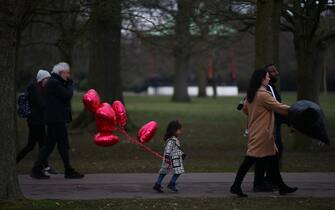 LONDON, ENGLAND - FEBRUARY 14: A child runs whilst holding a bunch of heart-shaped balloons at Greenwich Park on Valentines Day on February 14, 2021 in London, England. Frozen fountains and ponds around the capital started to thaw as temperatures returned to positive territory on Sunday. (Photo by Hollie Adams/Getty Images)