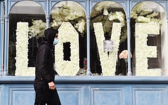 BURSLEM, ENGLAND - MARCH 15: A man wearing a mask walks past a love sign made out of flowers in a shop window on March 15, 2021 in Burslem, England. (Photo by Nathan Stirk/Getty Images)