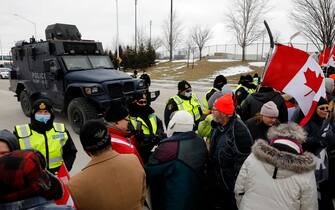 Protestors against Covid-19 vaccine mandates are stopped by police as they block the entrance to the Ambassador Bridge in Windsor, Ontario, Canada, on February 12, 2022. - Police in Canada were positioning Saturday to clear the bridge on the US border, snarled for days by truckers protesting against vaccination rules, an AFP journalist observed. "We urge all demonstrators to act lawfully & peacefully," police in Windsor, Ontario, home to the Ambassador Bridge, tweeted in announcing the deployment. (Photo by JEFF KOWALSKY / AFP) (Photo by JEFF KOWALSKY/AFP via Getty Images)