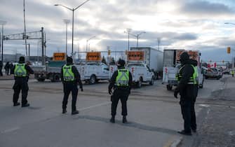 Police officers move in to clear traffic and protesters blocking access to the Ambassador Bridge during a demonstration in Windsor, Ontario, Canada, on Saturday, Feb. 12, 2022. Police in Ontario have begun to clear out people who've been blocking the Ambassador Bridge that connects Canada with Detroit in a protest against Covid-19 restrictions. Photographer: Galit Rodan/Bloomberg