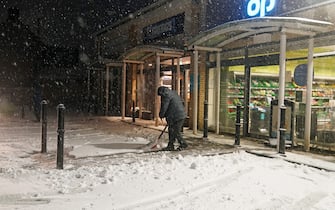A man shovels snow in front of his shop