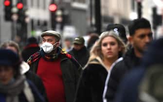 epa09774274 A man wears a mask as he walks on Oxford Street in London, Britain, 20 February 2022. England is expected to end all Covid-19 restrictions in the coming days with people in England no longer having to self-isolate after a positive test, Downing Street has said.  EPA/NEIL HALL