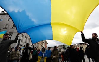 People hold an Ukrainian flag as they attend a march against Russian agression to the Ukraine, in Krakow, Poland on February 20, 2022. The demonstration is organized as the Russian-Ukrainian border tension continues. (Photo by Jakub Porzycki/NurPhoto via Getty Images)