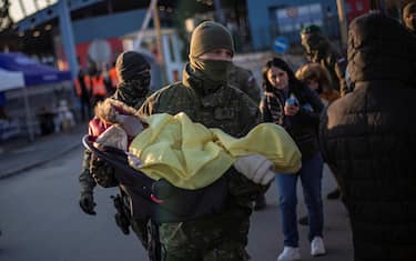 epa09788417 A Slovak soldier carris a baby in car seat as people fleeing Ukraine arrive to Slovakia, at border crossing in Vysne Nemecke, Slovakia, 27 February 2022. Slovakia said it will let fleeing Ukrainians into the country following Russia's military operation in Ukraine. The Slovak Police Force announced on social media that people not holding a valid travel document will also be eligible for entry on an individual basis.  EPA/MARTIN DIVISEK