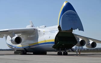 People wearing protective equipment are seen by an Antonov-225 Mriya cargo plane after its arrival with medical cargo from China, at an airfield in Gostomel outside Kiev on April 23, 2020, amid the COVID-19 coronavirus pandemic. (Photo by GENYA SAVILOV / AFP) (Photo by GENYA SAVILOV/AFP via Getty Images)