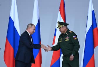 epa09426052 Russian President Vladimir Putin (L) shakes hands with Defence Minister Sergei Shoigu (R) during the opening ceremony of the International Military-Technical Forum 'Army-2021' held in the Patriot Park, in Kubinka outside Moscow, Russia, 23 August 2021.  EPA/KIRILL KUDRYAVTSEV/AFP POOL