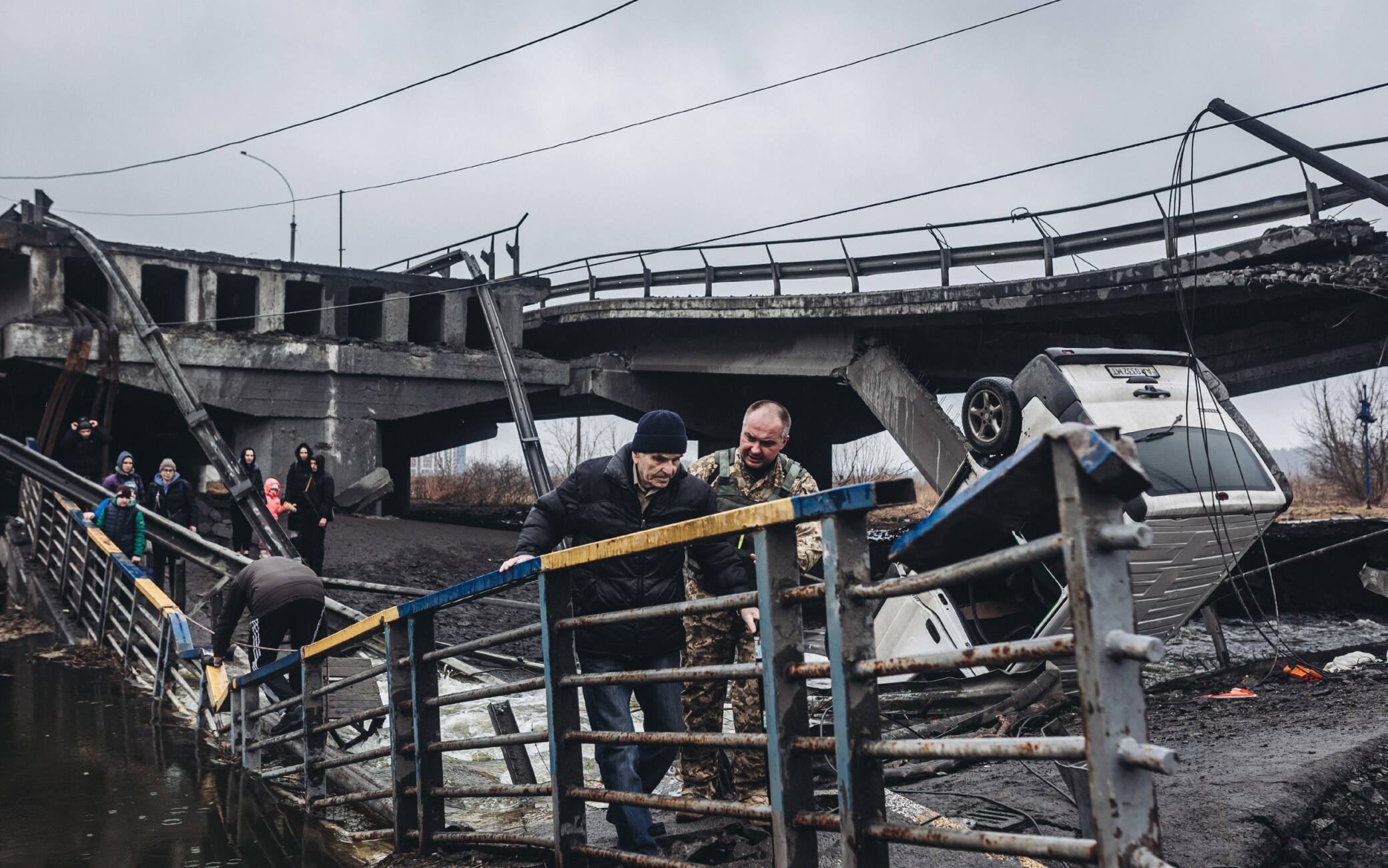 Civili attraversano il ponte distrutto