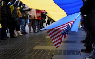epa09782513 An attendee holds an American flag while moving part of the Ukrainian flag with others during the Stop Putin' rally at Times Square in New York, New York, USA, 24 February 2022. Russian troops launched a major military operation on Ukraine on 24 February, after weeks of intense diplomacy and the imposition of Western sanctions on Russia aimed at preventing an armed conflict in Ukraine.  EPA/SARAH YENESEL