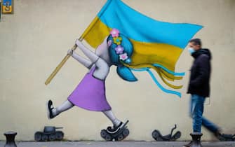 TOPSHOT - A bystander walks past a fresco by street artist Seth depicting a girl with a Ukrainian flag walking on tanks in Paris on March 01, 2022. - RESTRICTED TO EDITORIAL USE - MANDATORY MENTION OF THE ARTIST UPON PUBLICATION - TO ILLUSTRATE THE EVENT AS SPECIFIED IN THE CAPTION (Photo by JOEL SAGET / AFP) / RESTRICTED TO EDITORIAL USE - MANDATORY MENTION OF THE ARTIST UPON PUBLICATION - TO ILLUSTRATE THE EVENT AS SPECIFIED IN THE CAPTION / RESTRICTED TO EDITORIAL USE - MANDATORY MENTION OF THE ARTIST UPON PUBLICATION - TO ILLUSTRATE THE EVENT AS SPECIFIED IN THE CAPTION (Photo by JOEL SAGET/AFP via Getty Images)