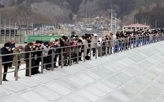 Persone in raccoglimento durante la commemorazione della catastrofe di Fukushima
