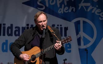 13 March 2022, Saxony, Leipzig: Burkhard Jung (SPD), mayor of the city of Leipzig, plays guitar and sings during a demonstration on Augustusplatz. Several thousand people protested against the war in Ukraine. Photo: Sebastian Willnow/dpa-Zentralbild/dpa (Photo by Sebastian Willnow/picture alliance via Getty Images)