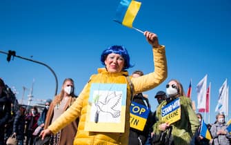 13 March 2022, Hamburg: A participant of a demonstration against the Ukraine conflict stands on the Jungfernstieg and waves a Ukrainian flag. Photo: Daniel Bockwoldt/dpa (Photo by Daniel Bockwoldt/picture alliance via Getty Images)