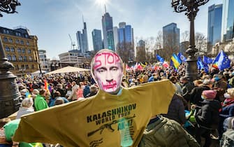 13 March 2022, Hessen, Frankfurt/Main: A demonstrator holds a poster showing Russian President Putin with the inscription "Stop War" and a T-shirt with the inscription "Kalashnikov World Tour". Thousands of people had gathered under the slogan "Stop the war! Peace and solidarity for the people of Ukraine" gathered in front of the Alte Oper. A broad alliance of more than 50 organizations had called for large-scale demonstrations in several German cities. Photo: Frank Rumpenhorst/dpa (Photo by Frank Rumpenhorst/picture alliance via Getty Images)